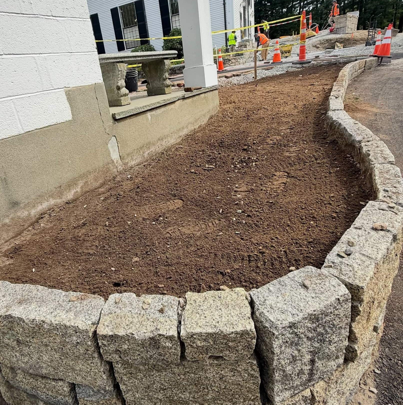 Before: a curved granite-edged bed at a commercial building, bare dirt